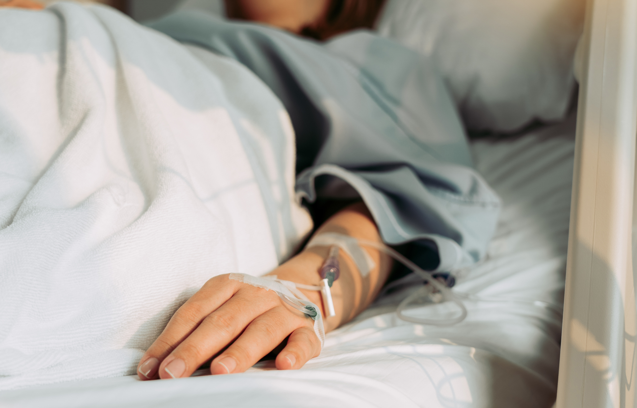 Hand von Patientin mit Zugängen im Krankenhausbett
