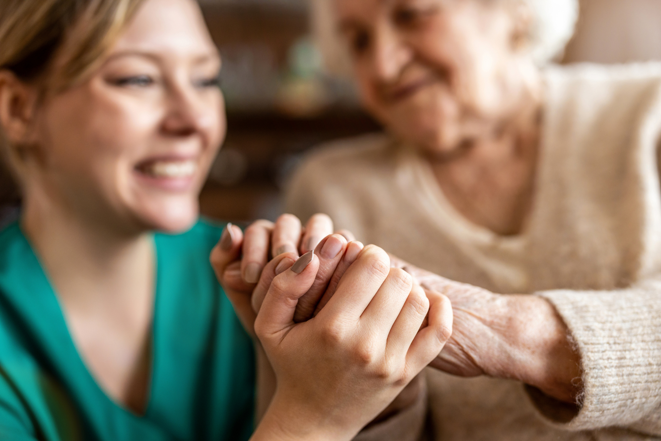 Krankenpflegerin hält die Hände einer alten Frau